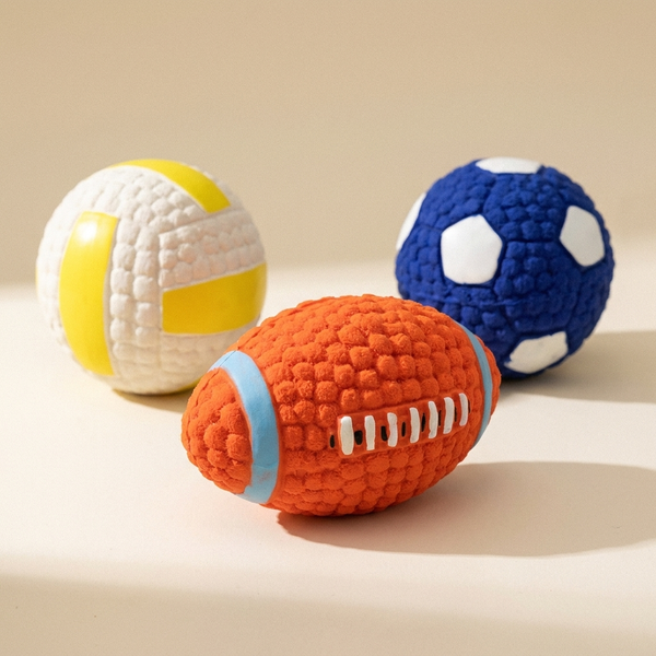 Squeaky textured dog play balls on a cream studio background
