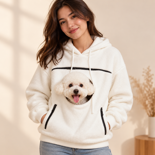 Woman wearing the white bouclé pet carrier hoodie with a small white dog peeking out of the front pouch