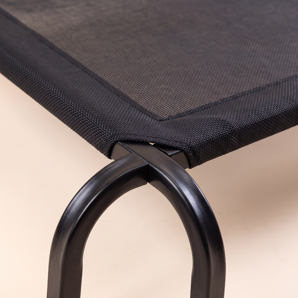 Close-up of the elevated dog cot corner: steel tube frame, curved leg and taut mesh