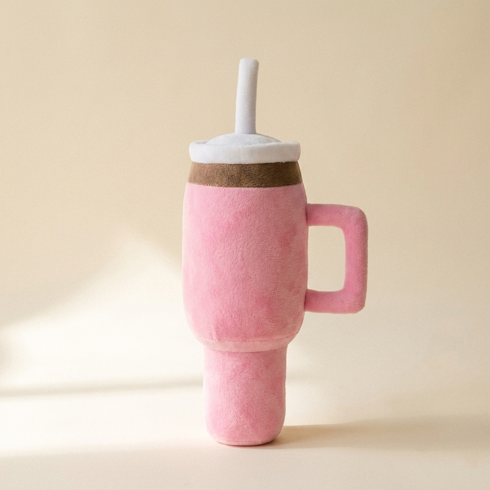 Pink squeaky cup plush dog toy on cream studio background
