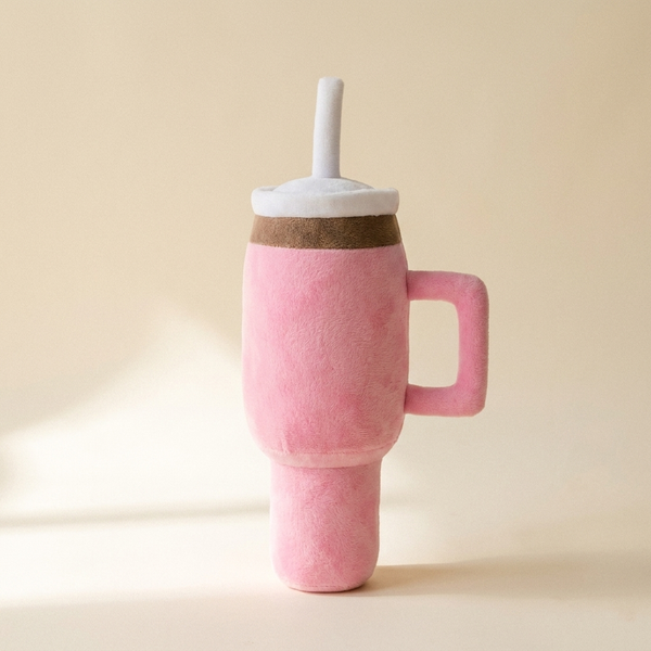 Pink squeaky cup plush dog toy on cream studio background
