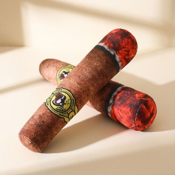 Funny cigar-shaped plush squeaky dog toy on a cream studio background