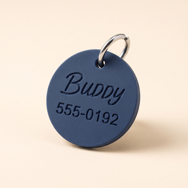 Navy silicone pet ID tag engraved with BUDDY and phone number, studio product photo