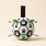 Dog soccer ball with green grab straps and a black carry loop, black and white paw-print panels, front view