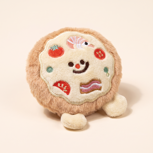 Round pizza squeaky plush dog toy with a smiling face, embroidered toppings and little feet