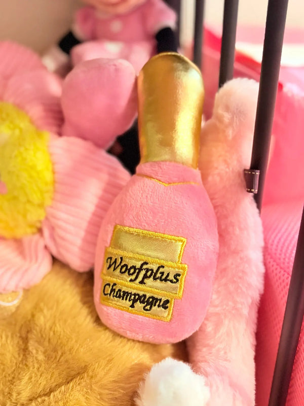 Customer photo: pink champagne bottle plush dog toy among pink plush toys
