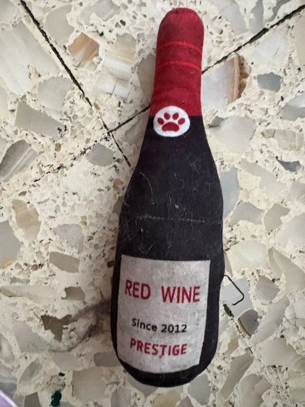 Customer photo: red wine bottle plush dog toy on a tiled floor